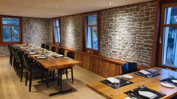 Stijlvolle eetkamer met lange houten tafels, stenen muren en moderne decoratie