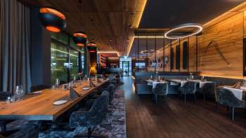 Elegante eetkamer met moderne verlichtingselementen en houten lambrisering aan de muren.