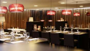 Stijlvolle eetkamer met donkere meubels, rode designlampen en een elegante sfeer