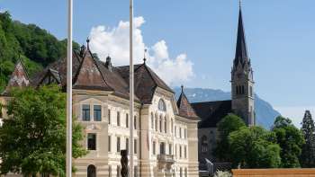  Uitzicht door een ronde boog op de regeringswijk in Vaduz met het parlementsgebouw en de St Florin Kathedraal.