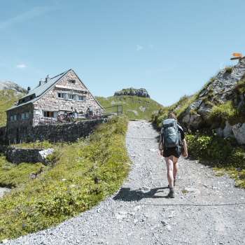 Wandelaar met rugzak over een bergpad richting de Pfälzerhütte in de Liechtensteinse Alpen