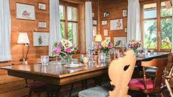 Uitnodigende eetkamer met houten plafond, liefdevol gedekte tafel en helder uitzicht vanuit het raam