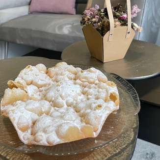 Fasnachtsküachli op een glazen plaat, geserveerd in een gezellige sfeer met decoraties op de achtergrond