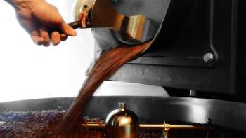 Vers gebrande koffiebonen stromen van een brandmachine in een opvangbak