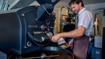 Man brandt koffiebonen op een moderne brandmachine in een koffiebranderij