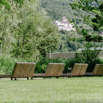 Rustige ligweide met houten ligstoelen in natuurpark Haberfeld, met uitzicht op het kasteel op de achtergrond.