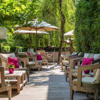 Comfortabele zithoek met kussens, planten en parasols op het terras van het Park Hotel Sonnenhof in Vaduz, Liechtenstein