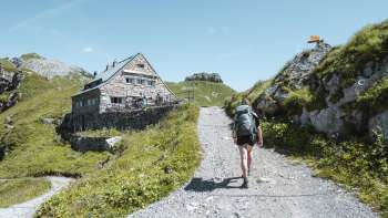 Wandelaar met rugzak over een bergpad richting de Pfälzerhütte in de Liechtensteinse Alpen