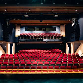 Uitzicht vanaf het podium op rode rijen stoelen en lichttechniek in het moderne auditorium van het TAK Theater Liechtenstein