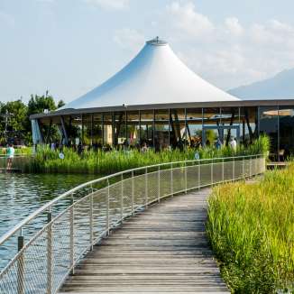 Steg aan het zwemmeer Grossabünt in Gamprin met een modern paviljoen en uitzicht op de bergen op de achtergrond