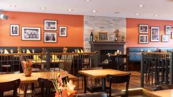 Gezellige eetzaal in restaurant New Castle met warme kleuren, een open haard en stijlvolle houten tafels