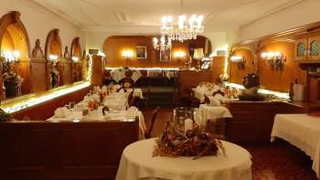 Langwerpige zaal met feestelijk gedekte tafels, elegante decoraties en warme verlichting Langwerpige zaal met feestelijk gedekte tafels, elegante decoraties en warme verlichting