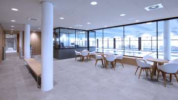 Lichte zithoek in het Triesen binnenzwembad met uitzicht op het zwembad door de glazen voorkant.