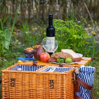 Picknickmand met regionale specialiteiten, vers brood, fruit en wijn, liefdevol gerangschikt in een weiland midden in de natuur.
