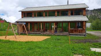 Buitenopname van de Malbipark-Bistro met een speeltuin en weiland op de voorgrond