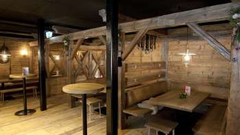 Gezellige zithoek met houten banken en tafels in de traditionele Malbuner Lädeli stijl