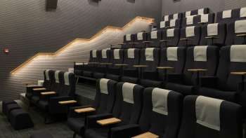 Moderne bioscoopzaal in de Skino Schaan met comfortabele stoelen, tafeltjes en gedempte verlichting.