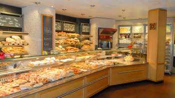 Zicht op de verkoopruimte van de Amann bakkerij en banketbakkerij met een volle toonbank en veel lekkers