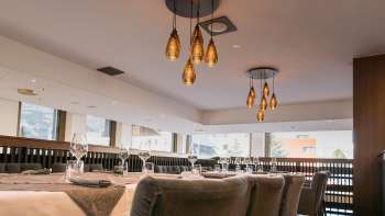 Modern restaurantgedeelte met uitzicht op de etalage en stijlvolle hanglampen.