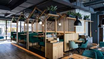Modern restaurant met stijlvolle houten constructie, groen gestoffeerde stoelen en creatieve kamerindeling Modern restaurant met stijlvolle houten constructie, groen gestoffeerde stoelen en creatieve kamerindeling