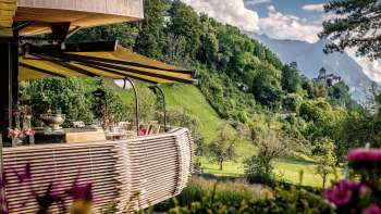 Zonnig terras met bloeiende bloemen en elegant gedekte tafels met uitzicht op de vallei