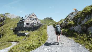 Wandelaar met rugzak over een bergpad in de richting van de Pfälzerhütte in de Liechtensteinse Alpen.