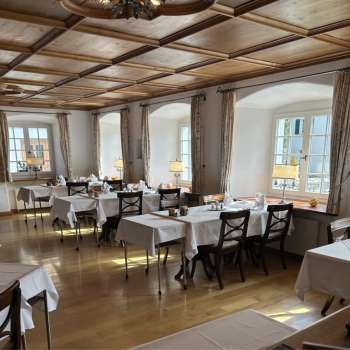 Lichte, klassieke eetkamer met witte tafelkleden en houten vloer.