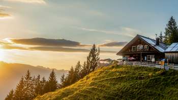 Gadafura hut op een zonnige bergweide met uitzicht op de bergen en zonsondergang