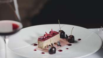 Elegant dessert op een wit bord, versierd met kersen en chocolade