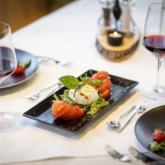 Verse tomaat en mozzarella salade met rode wijn op een gedekte tafel in het JUFA Hotel Malbun