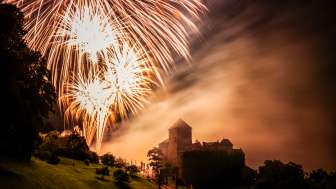 Kasteel van Vaduz in Liechtenstein bij nacht met groot vuurwerk in de lucht - sfeervolle opname met licht en mist