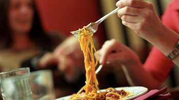 Persoon raapt spaghetti op met een vork van een bord in Brasserie Burg