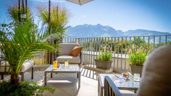 Zonnig terras met moderne loungemeubelen en Alpenpanorama op de achtergrond