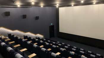 lik van het grote bioscoopscherm in de Skino Schaan, met rijen comfortabele stoelen in een donker design.