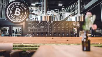 Moderne brouwerijbar met groot logo en glimmende kranen op de voorgrond.