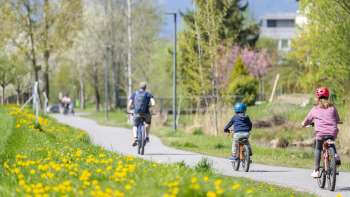 Fietsen met het gezin op het lentefietspad in natuurpark Haberfeld, omringd door bloeiende weiden en bomen.