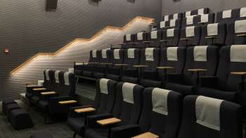 Moderne bioscoopzaal in de Skino Schaan met comfortabele stoelen, tafeltjes en gedempte verlichting.