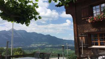 Traditioneel gebouw met zonnig terras en bergpanorama op de achtergrond