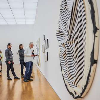 Bezoekers bekijken moderne kunstwerken in een galerie van het Kunstmuseum Liechtenstein met lichtgekleurde architectuur en houten vloeren