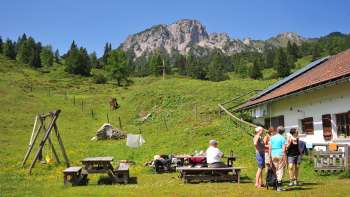 Uitzicht op de bergen vanaf Alpe Guschg, waar verschillende mensen even pauzeren en genieten van het uitzicht