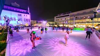 Mensen schaatsen 's avonds op de verlichte ijsbaan van Vaduz on Ice in het centrum van Vaduz