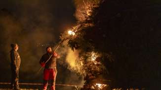Twee mannen steken 's nachts een groot vreugdevuur aan tijdens de traditionele Vonkzondag in Liechtenstein.