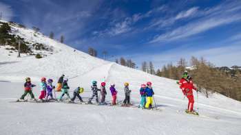 Skileraar in malbi-park (kinderpark) Malbun motiveert kinderen op de oefenpiste - perfecte omgeving voor hun eerste bochten in de sneeuw