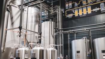 Zicht op de technische ruimte van de brouwerij met het complexe leidingsysteem en de moderne roestvrijstalen tanks.