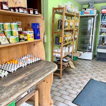  Binnenzicht van de boerderijwinkel van Aeulehof met rekken vol streekproducten, waaronder eieren en conserven.