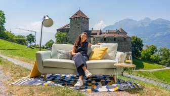 Ontspannen met uitzicht op het kasteel - moderne buitensetting voor het kasteel van Vaduz Vrouw zittend op een bank met uitzicht op kasteel Vaduz en de bergen van Liechtenstein, moderne buitensfeer met decoratie