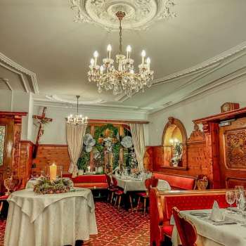 Close-up van een kroonluchter boven feestelijk gedekte tafels in een rustieke sfeer