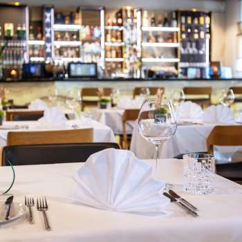  Smaakvol gedekte tafel in het Alpspitz restaurant met uitzicht op de bar op de achtergrond.