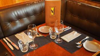 Gedekte tafel met menu in de leren zithoek van het Vanini Café