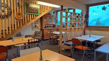 Gastenkamer met raam en decoratie - tafels en stoelen in een open kamer met grote ramen en uitzicht op de groene buitenruimte.